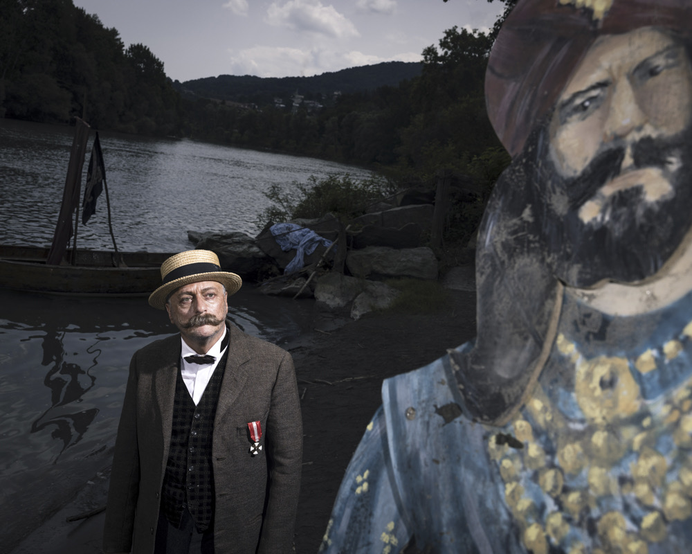 Un attore nei panni di Emilio Salgari sulla riva del fiume, accanto a una sagoma dipinta di Sandokan